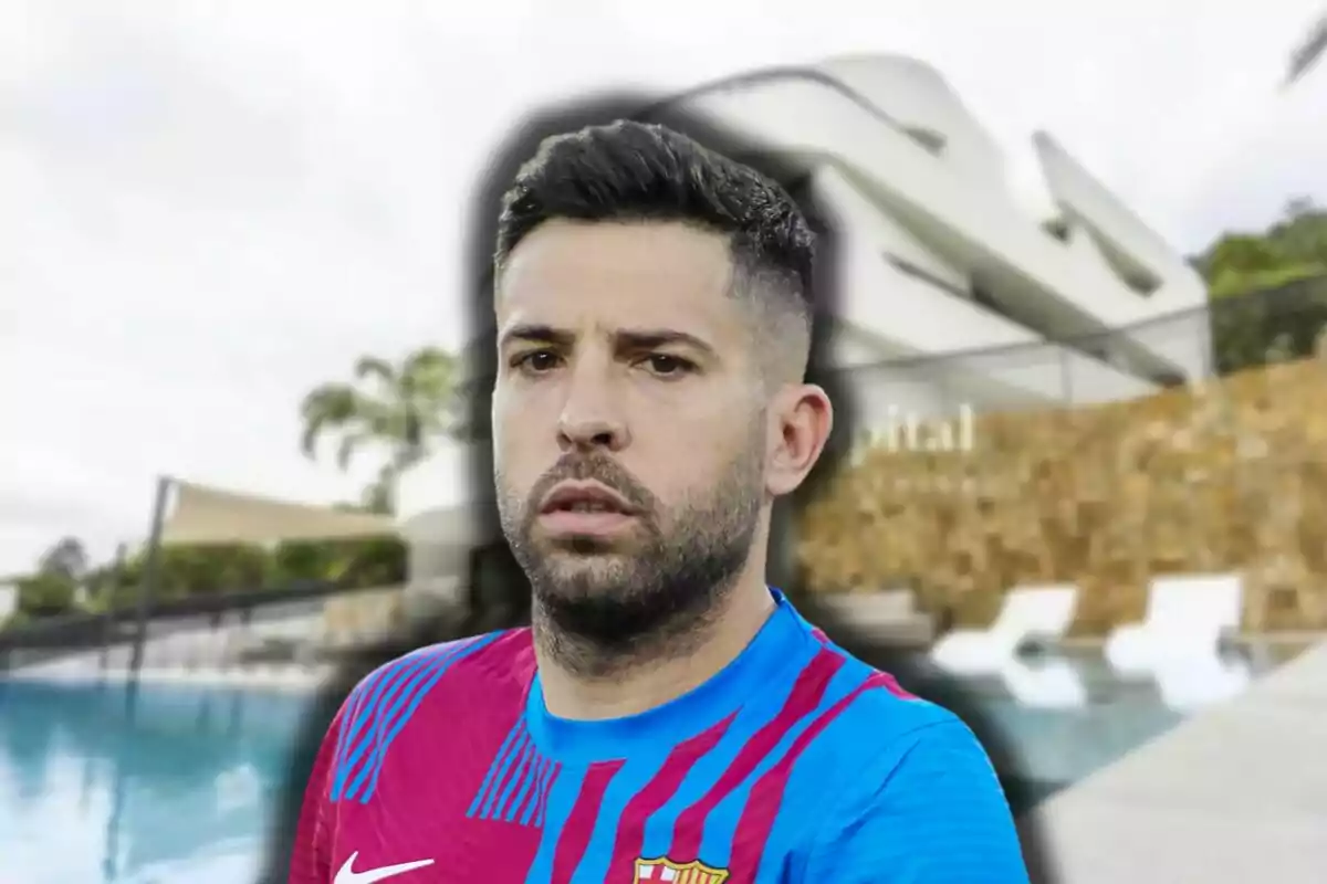 Jordi Alba amb samarreta de futbol blau i vermella davant d'una piscina i un edifici modern.