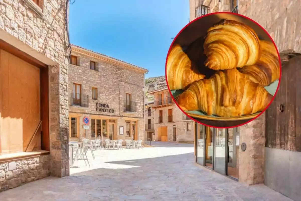 Un carrer empedrat amb edificis de pedra i una cafeteria al fons, amb una imatge superposada de croissants en un cercle vermell.