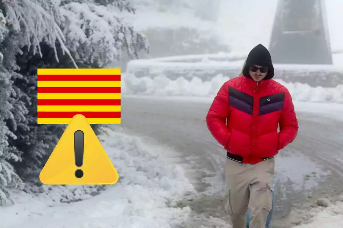 Un hombre con chaqueta roja camina por un camino nevado junto a un símbolo de advertencia y una bandera con franjas rojas y amarillas.