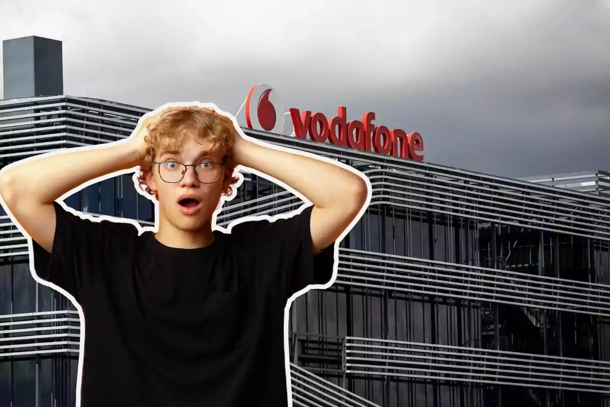 Un joven con expresión de sorpresa se encuentra frente a un edificio moderno con el logo de Vodafone en la parte superior.