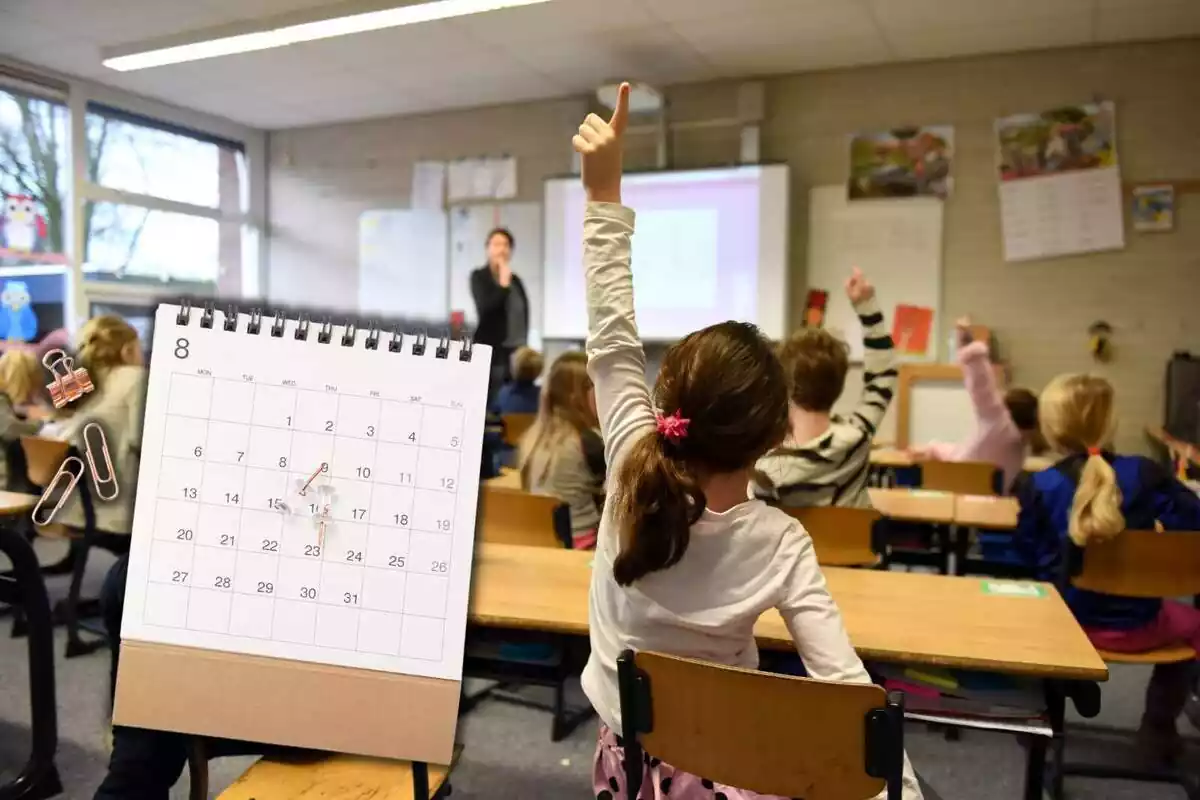 Muntatge amb una classe amb nens aixecant el braç i un calendari