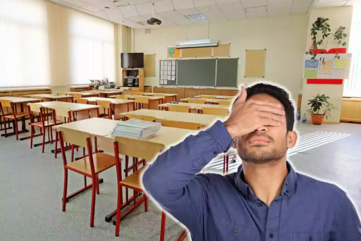 Un hombre con la mano en la cara frente a un aula vacía con escritorios y sillas.