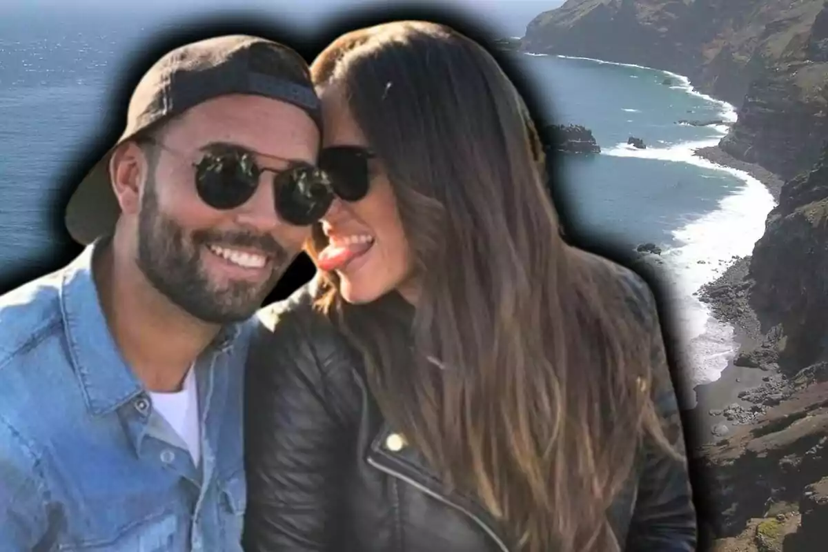 Una pareja sonriente con gafas de sol, formada por Anabel Pantoja y Omar Sánchez, posando frente a un paisaje costero de Canarias.