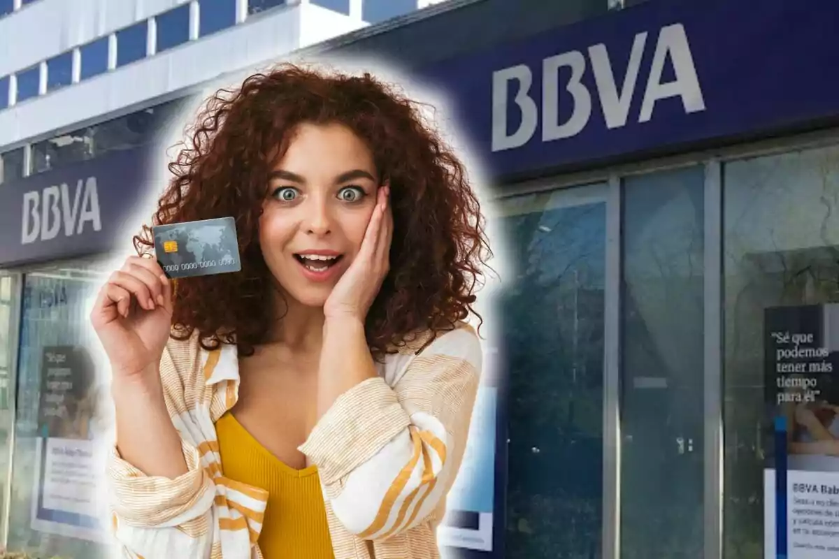 Dona sorpresa sostenint una targeta de crèdit davant d'una sucursal de BBVA.