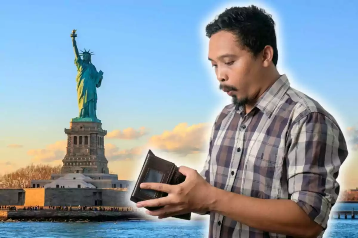 Un hombre con camisa de cuadros mira sorprendido su billetera vacía con la Estatua de la Libertad de fondo. Un hombre con camisa de cuadros mira sorprendido su billetera vacía con la Estatua de la Libertad de fondo.