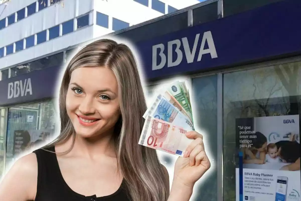 Una dona somrient sosté bitllets d'euro davant d'una sucursal del banc BBVA.