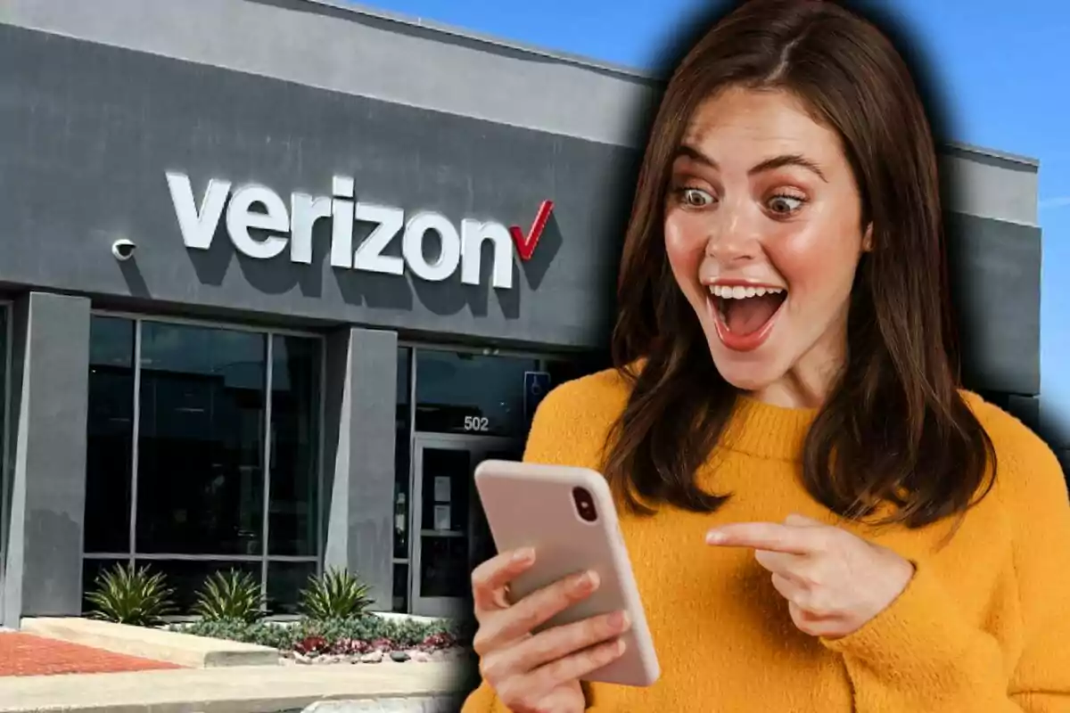 Una mujer emocionada mirando su teléfono frente a una tienda de Verizon.