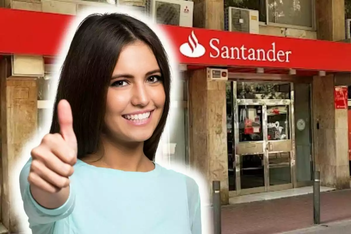 Una dona somrient amb el polze cap amunt davant d'una sucursal del banc Santander.