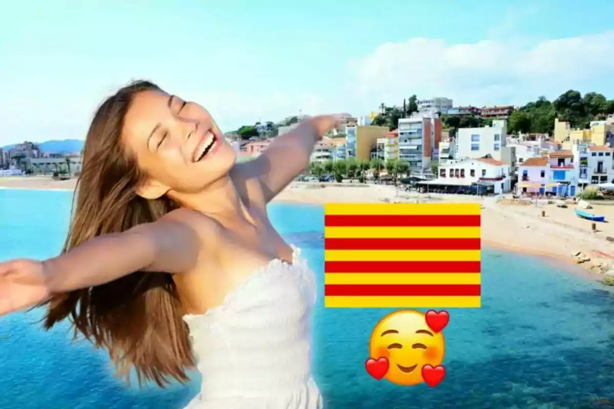 Una dona somrient amb els braços estesos davant d'una platja i edificis, amb una bandera catalana i un emoji somrient amb cors.