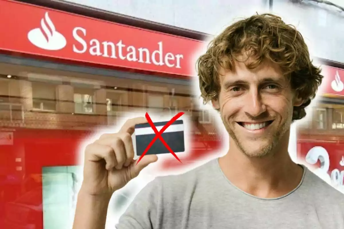 Un hombre sonriente sostiene una tarjeta tachada frente a una sucursal del banco Santander.