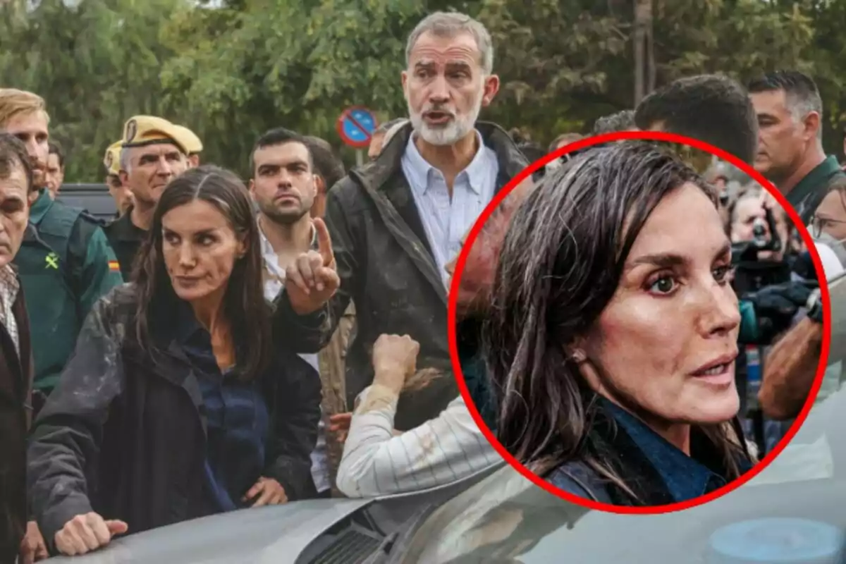 Un grup de persones, algunes amb uniforme, es troben en un entorn exterior; Letícia Ortiz en primer pla sembla estar parlant o assenyalant alguna cosa, mentre que Felip de Borbó darrere d'ella també sembla estar parlant.