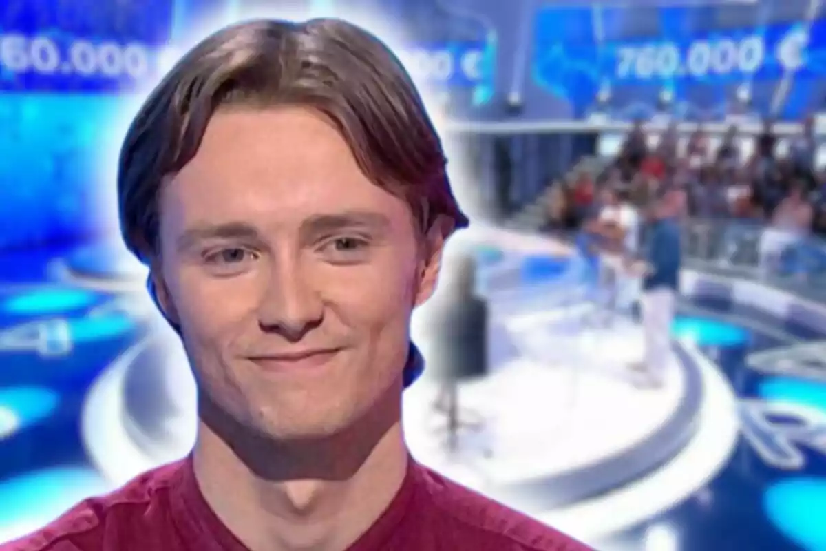 Manu Pascual smiles in a television studio with a blurred background showing a contest and a prize in euros.