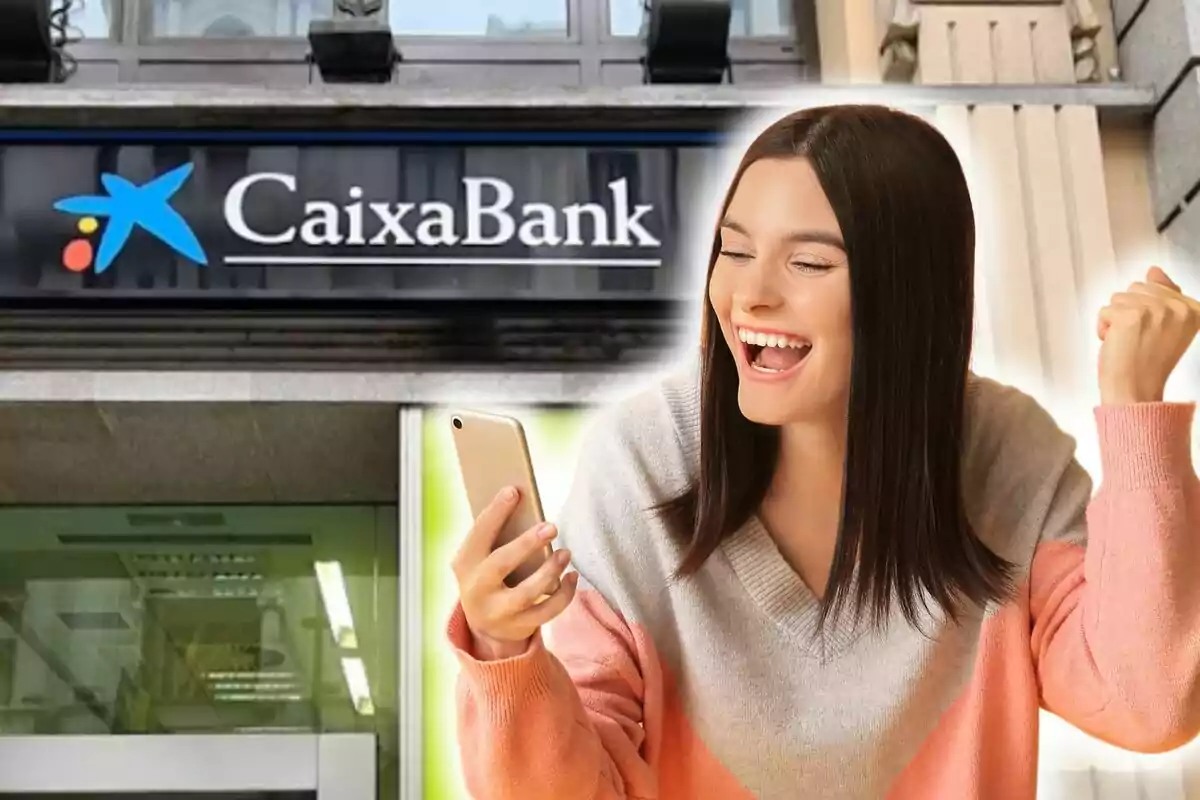 Una dona somrient sosté un telèfon mòbil davant d'una sucursal de CaixaBank.