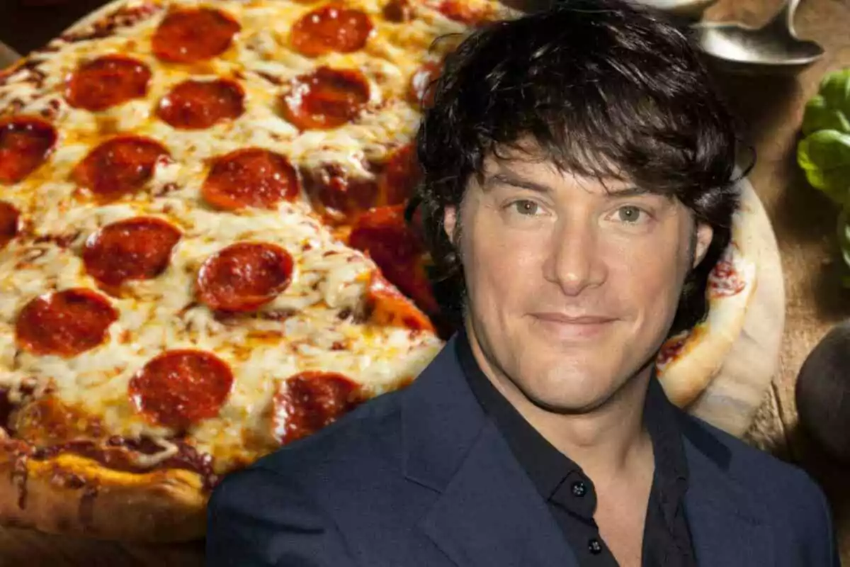 Jordi Cruz de cabello oscuro sonríe frente a una pizza de pepperoni.