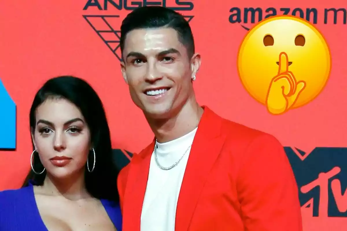 Georgina Rodríguez i Cristiano Ronaldo posant en un esdeveniment amb un fons vermell i un emoji de silenci.