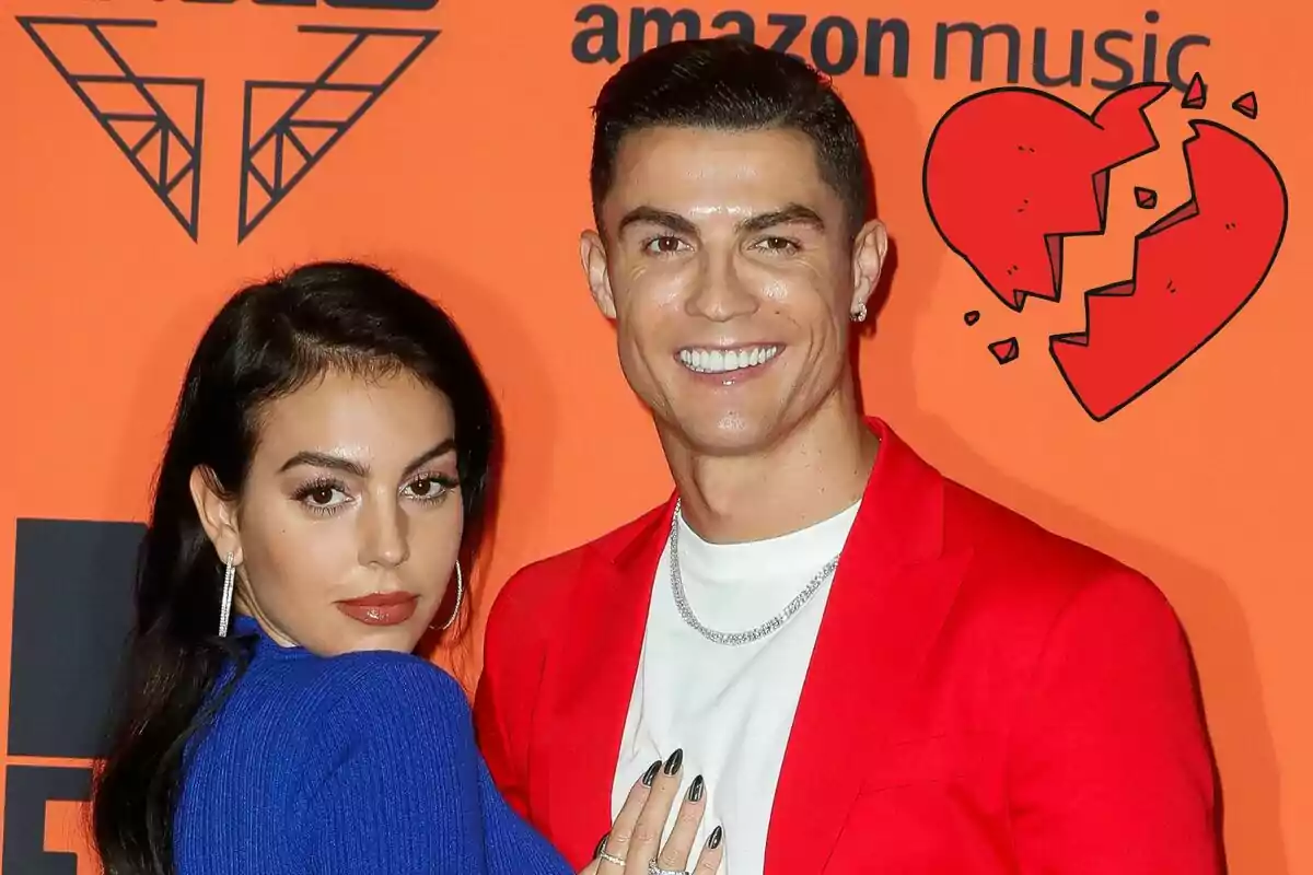 Georgina Rodríguez i Cristiano Ronaldo posant en un esdeveniment amb un fons taronja i un cor trencat dibuixat.