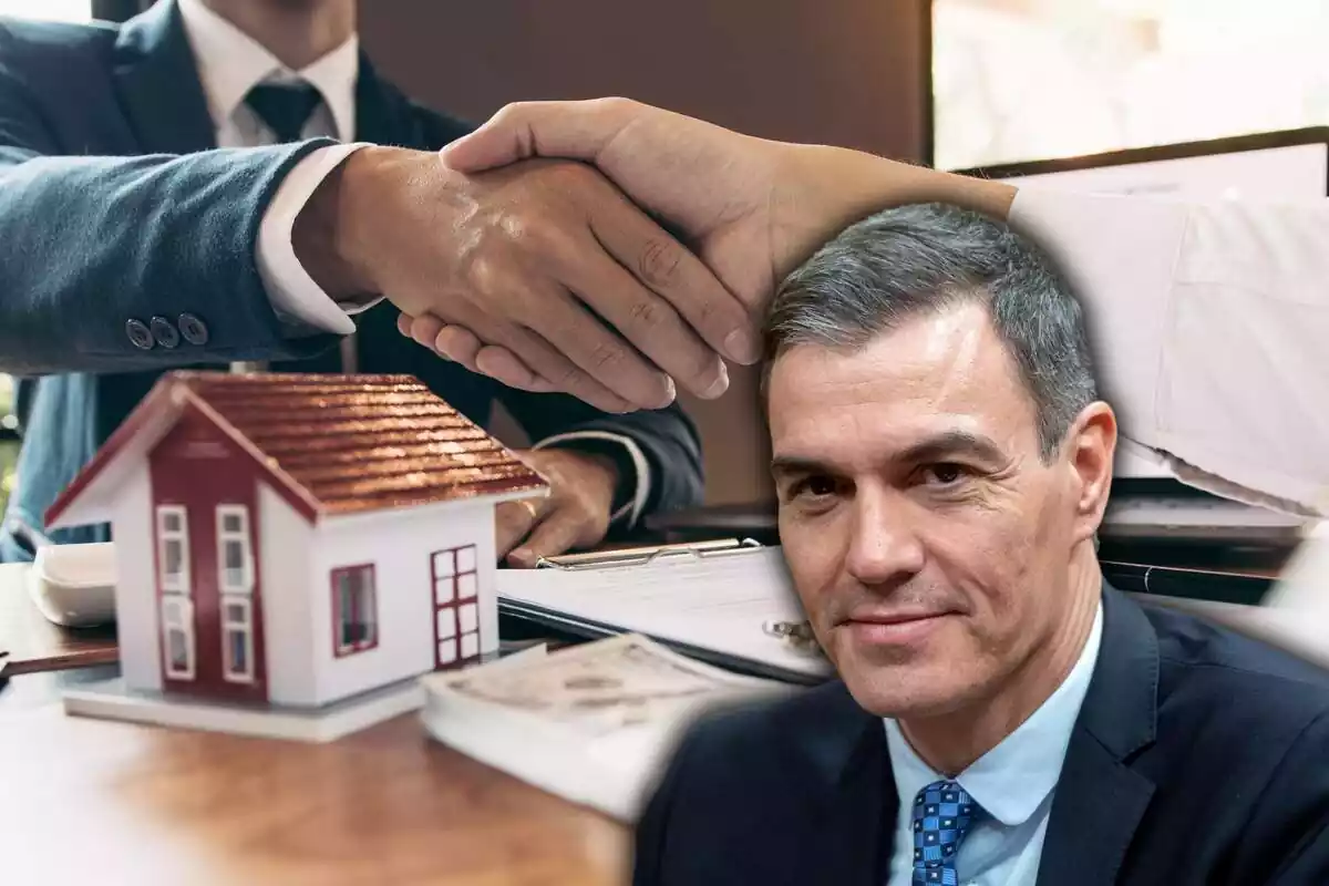 Dues persones es donen la mà, en una taula amb papers i una casa en miniatura, amb una imatge de Pedro Sánchez al lateral dret