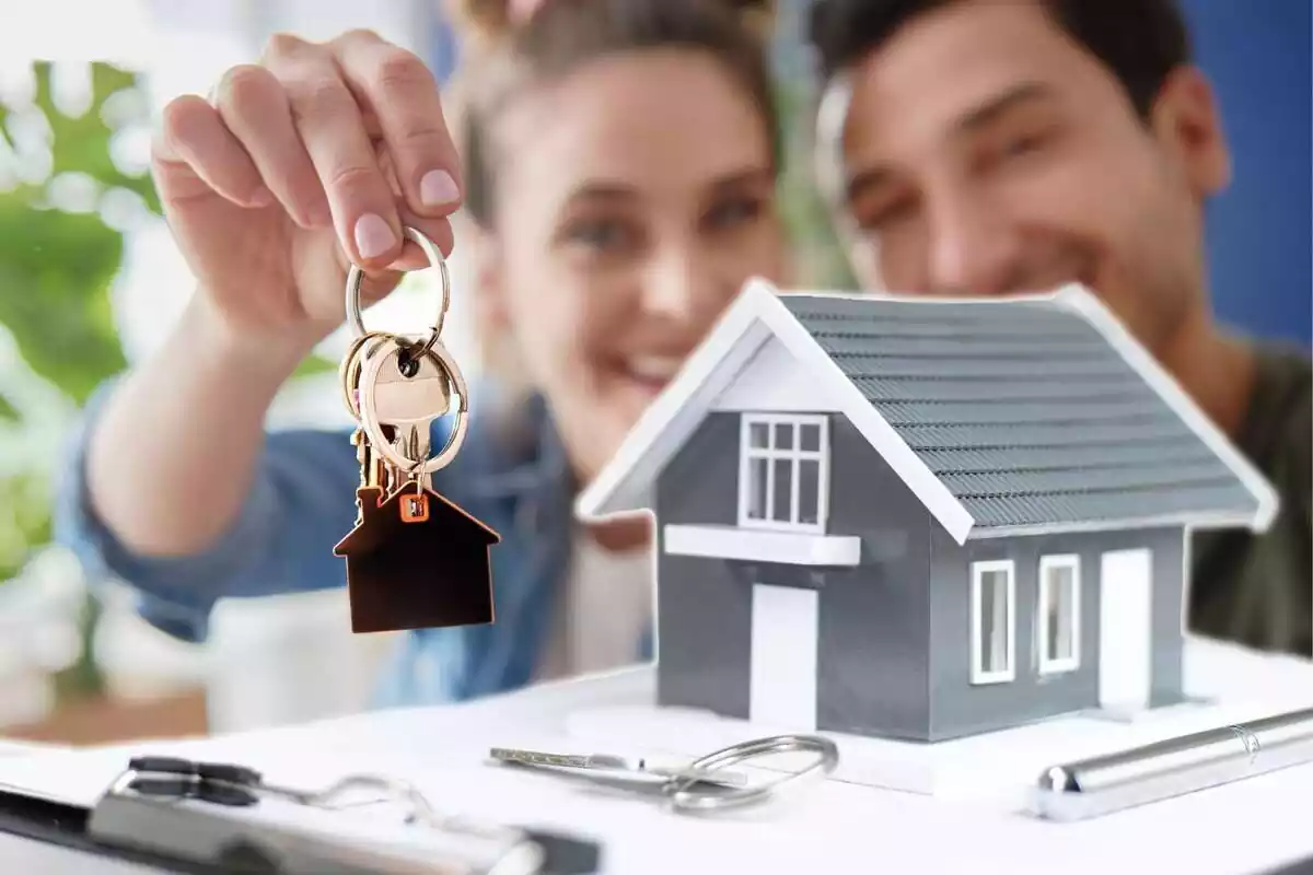 Muntatge amb una imatge d'una parella subjectant unes claus i una casa de joguina sobre un contracte hipotecari