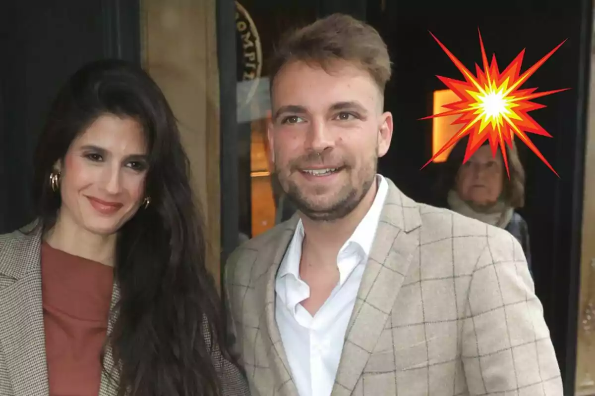 María Sánchez and José María Almoguera smiling while posing in front of a door with a graphic explosion effect in the background.