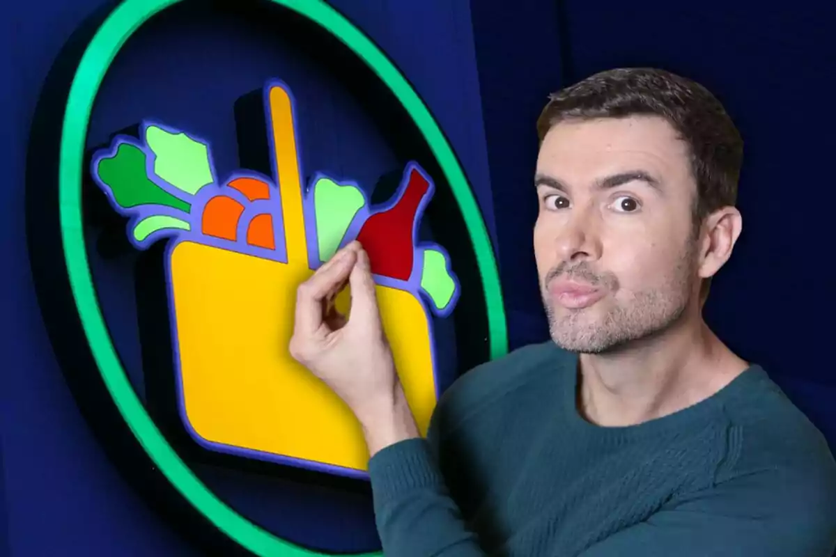 Home amb jersei verd posant de manera divertida al costat d’un cartell colorit de supermercat amb verdures i una ampolla