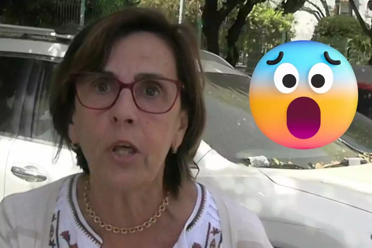 Mercedes Bernal con gafas rojas y expresión sorprendida junto a un emoji de cara asombrada frente a un coche blanco.