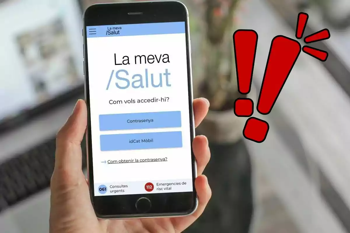 Persona sosteniendo un teléfono móvil que muestra una aplicación de salud en catalán con un icono de exclamación rojo al lado.