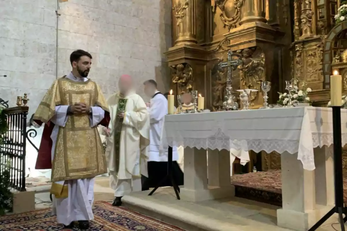 Un sacerdot amb vestimenta daurada està dret al costat d'un altar decorat amb canelobres i flors en una església. Un sacerdot amb vestimenta daurada està dret al costat d'un altar decorat amb canelobres i flors en una església.