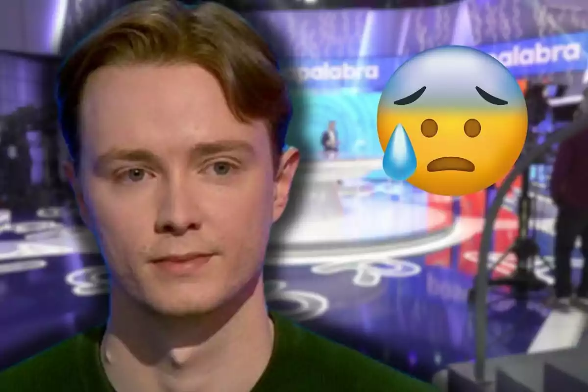 Manu d’expressió seriosa apareix en primer pla amb un gran emoji de cara trista i una llàgrima sobre un fons d’estudi de televisió desenfocat.