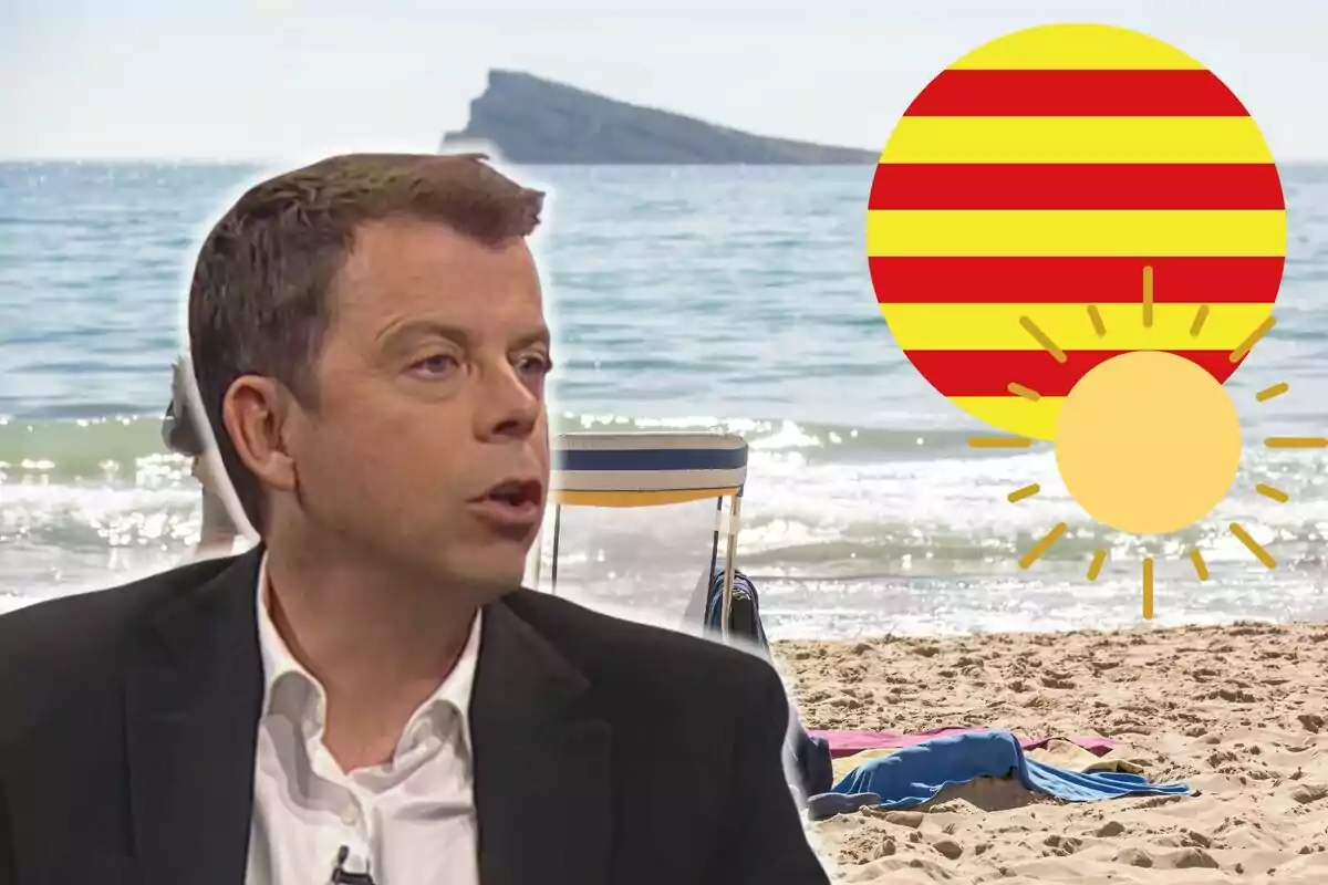 Francesc Mauri amb vestit fosc parlant davant d'una platja amb una cadira i una tovallola a la sorra, una bandera de Catalunya i un sol.