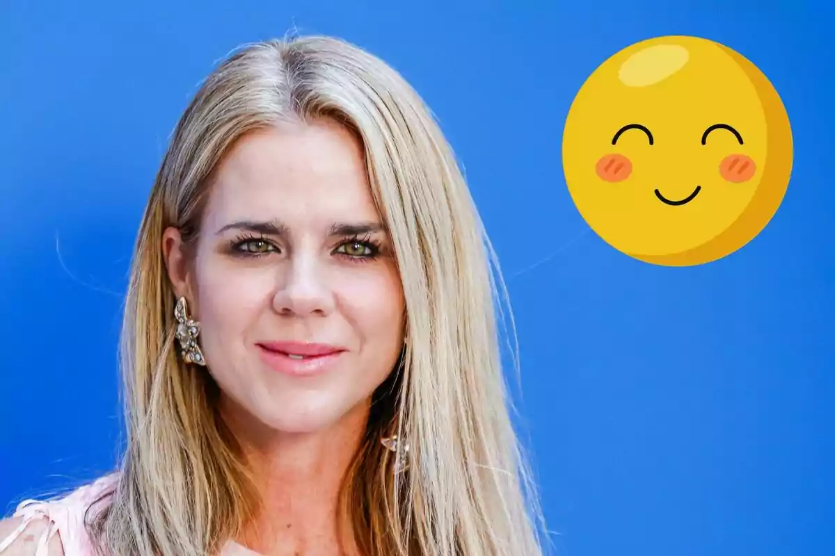 Amèlia Bono rossa amb pendents grans davant d'un fons blau al costat d'un emoji somrient.