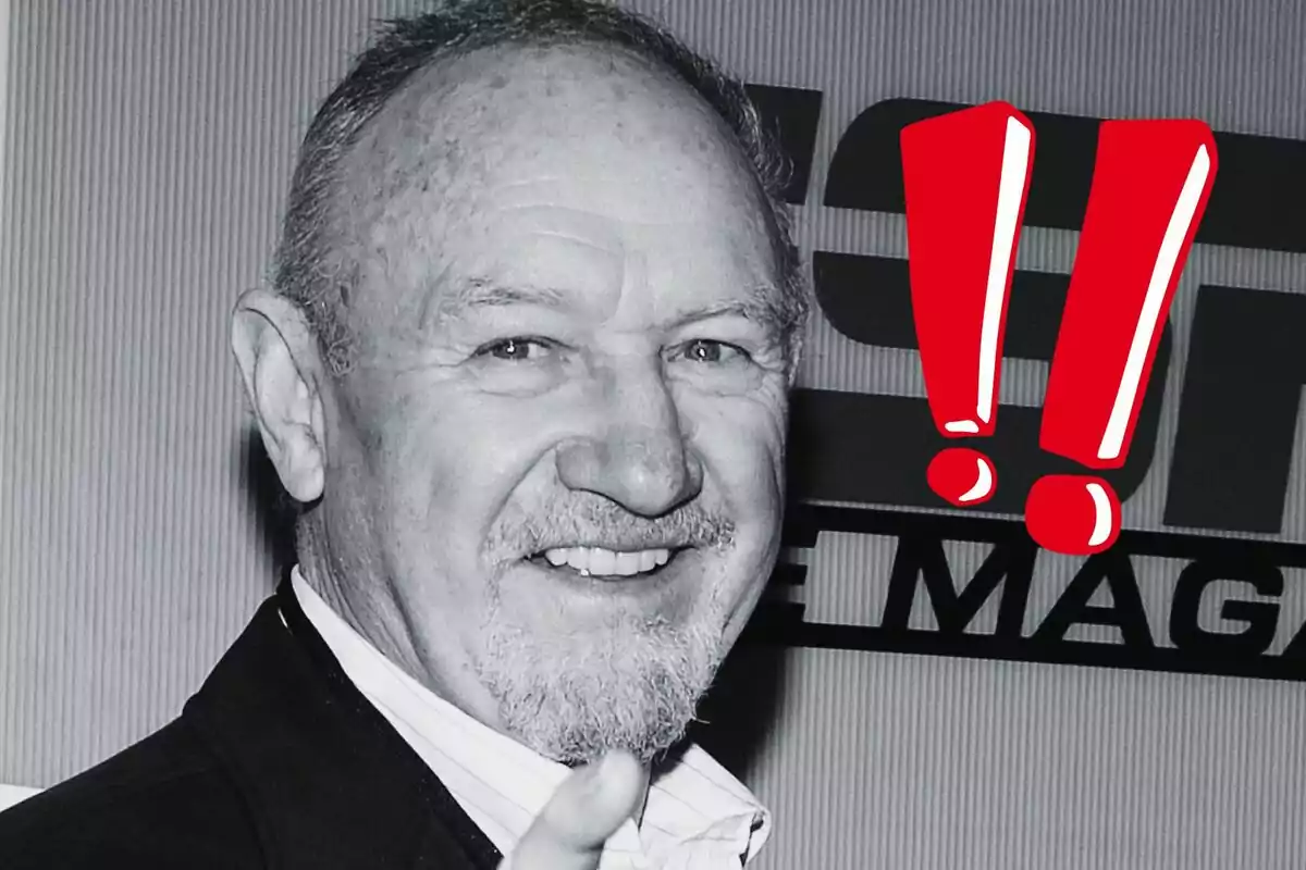 Gene Hackman sonriendo en una foto en blanco y negro con signos de exclamación rojos al lado.