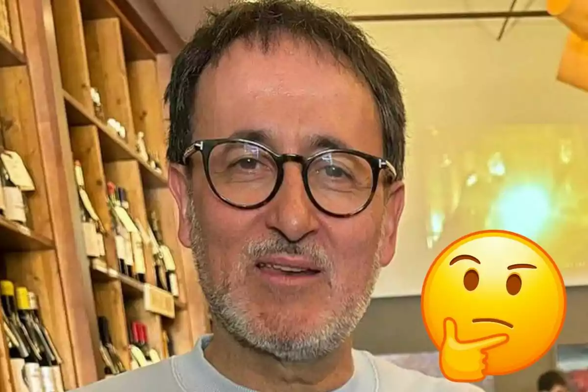 Xavier Graset amb ulleres i barba a una botiga de vins amb un emoji de cara pensativa superposat.