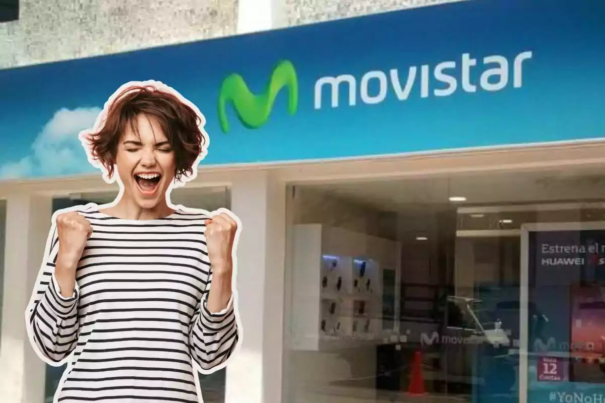 Una mujer sonriente con los puños levantados frente a una tienda de Movistar.