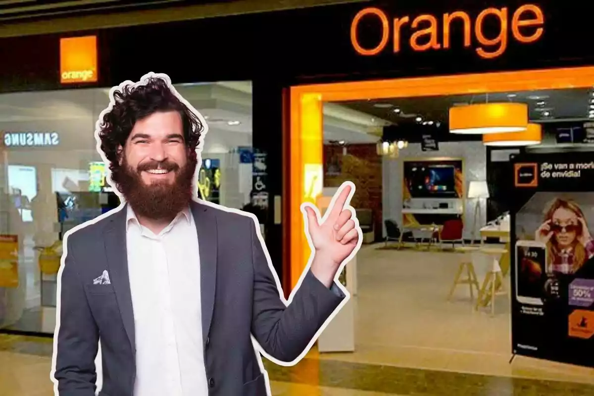 Un home somrient amb barba i vestit assenyala cap a una botiga d'Orange. Un home somrient amb barba i vestit assenyala cap a una botiga d'Orange.