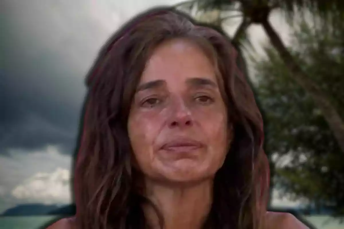 Carmen Alcayde amb expressió seriosa i fons de paisatge tropical amb cel ennuvolat.