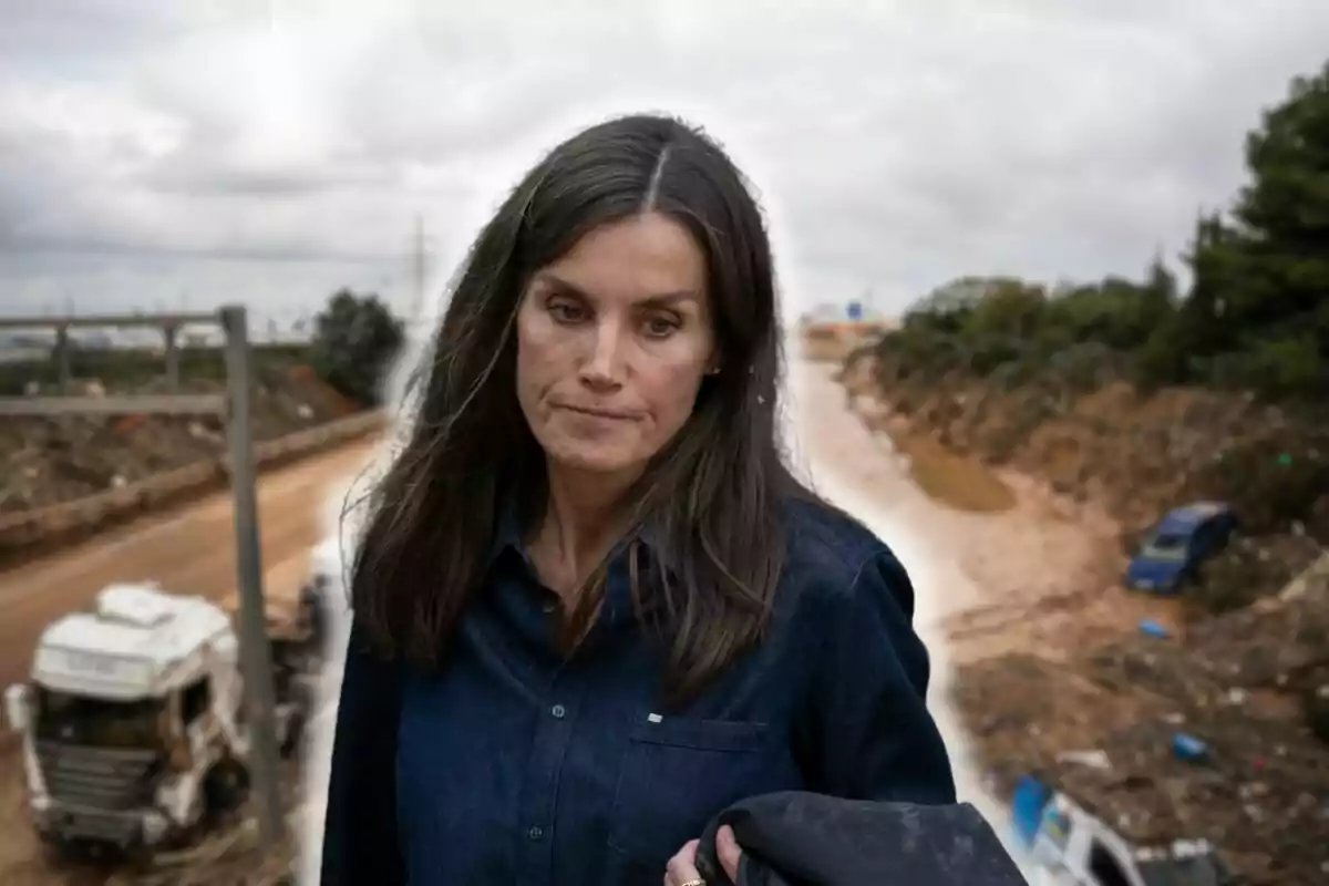 Letícia amb expressió seriosa camina per una àrea afectada per desastres naturals amb vehicles i runes al fons.