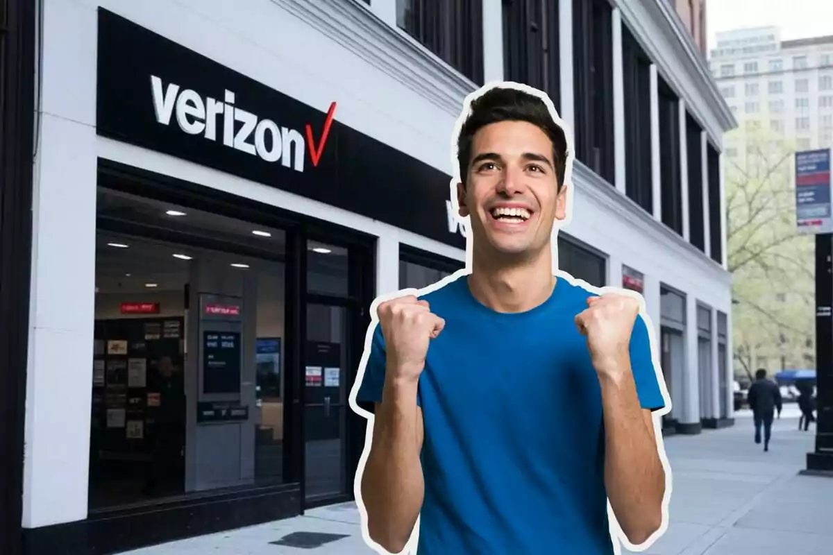 A smiling man in a blue jersey is in front of a Verizon store.