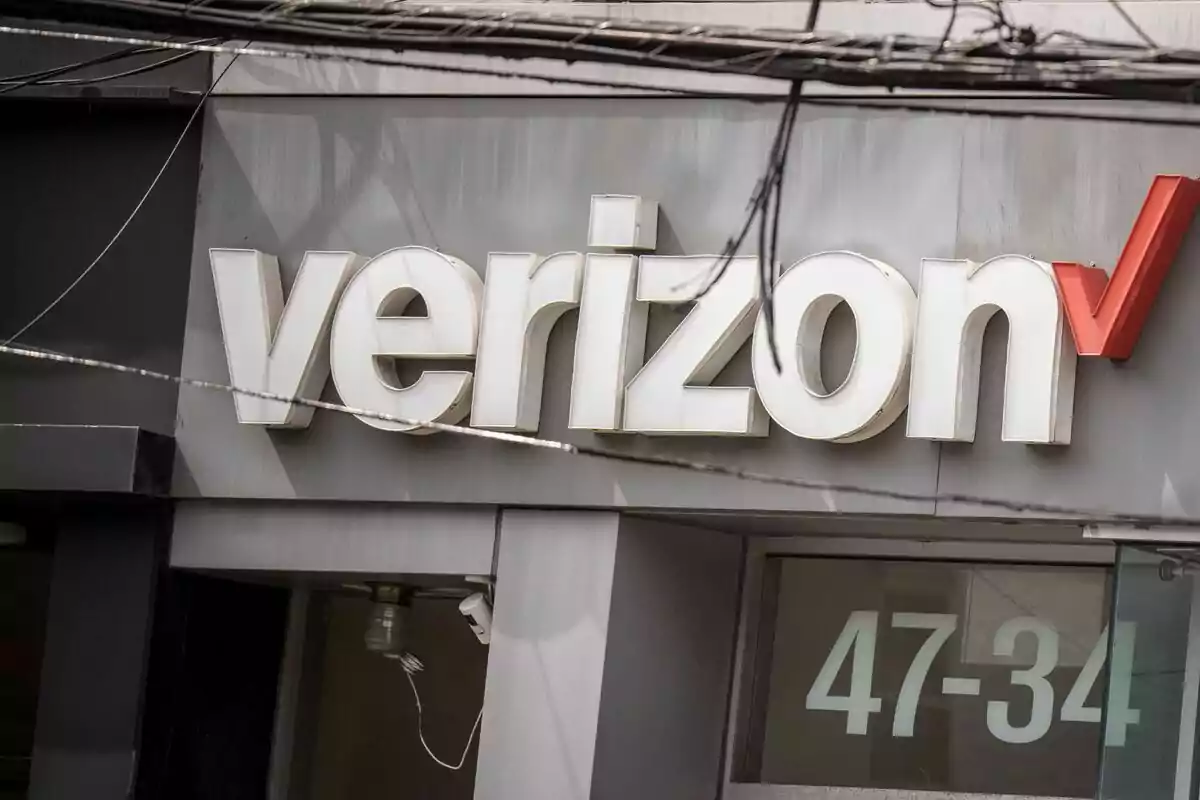 A Verizon sign on the facade of a building with visible electrical cables at the top. A Verizon sign on the facade of a building with visible electrical cables at the top.