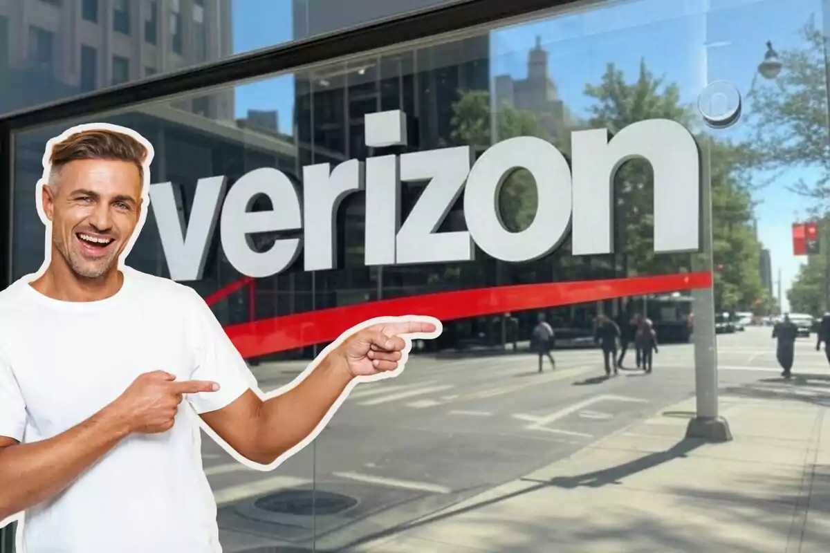 Man smiling and pointing at a Verizon sign on an urban street.