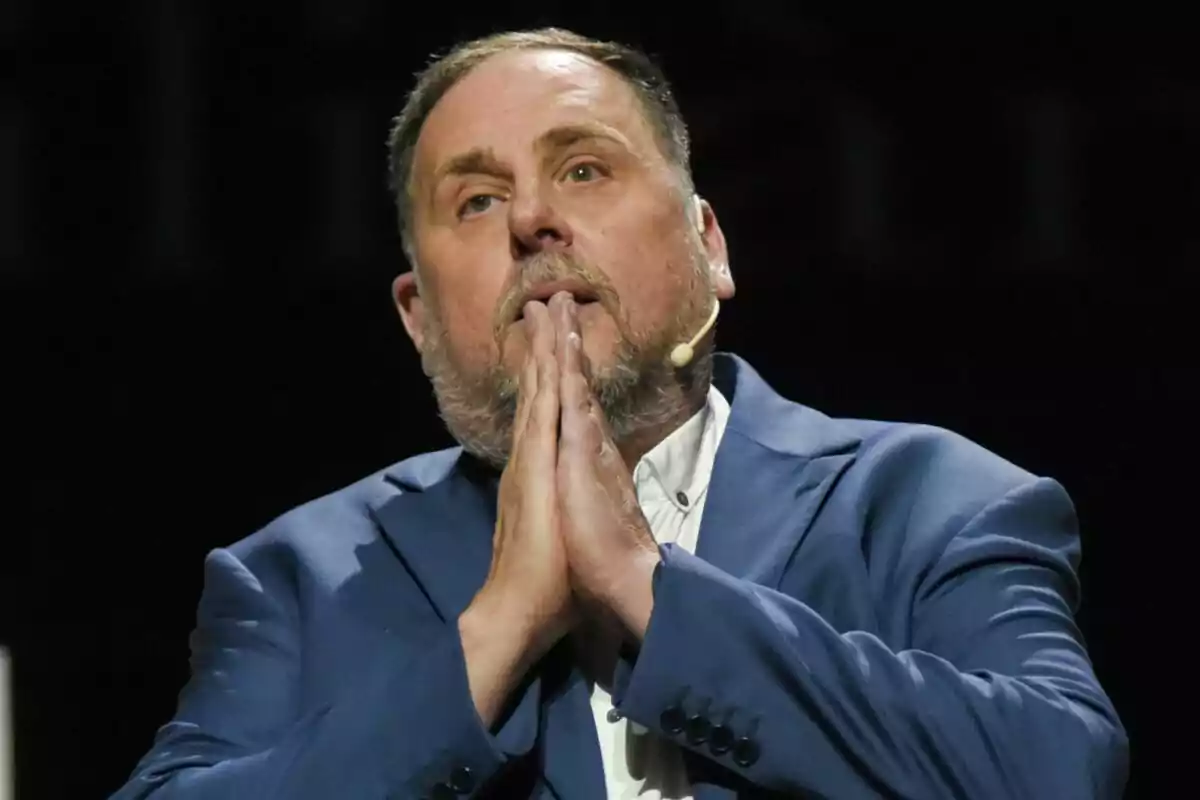 Oriol Junqueras in a blue suit, with his hands together and a microphone in his ear.