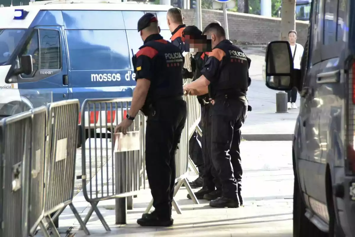 Policies col·locant tanques de seguretat en un carrer mentre una furgoneta de la policia està estacionada a prop.