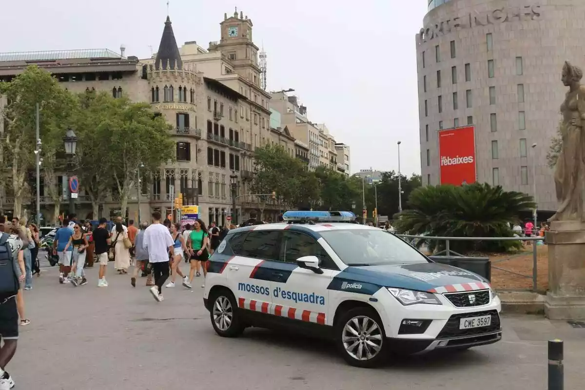 Plànol general de la plaça Catalunya de Barcelona amb un cotxe dels Mossos en primer pla