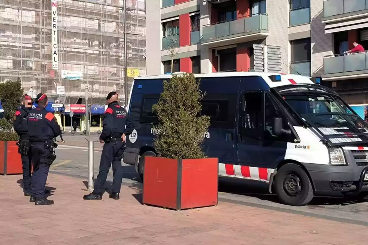 Imatge de tres mossos d'esquadra drets al costat d'una furgoneta policial a Calella