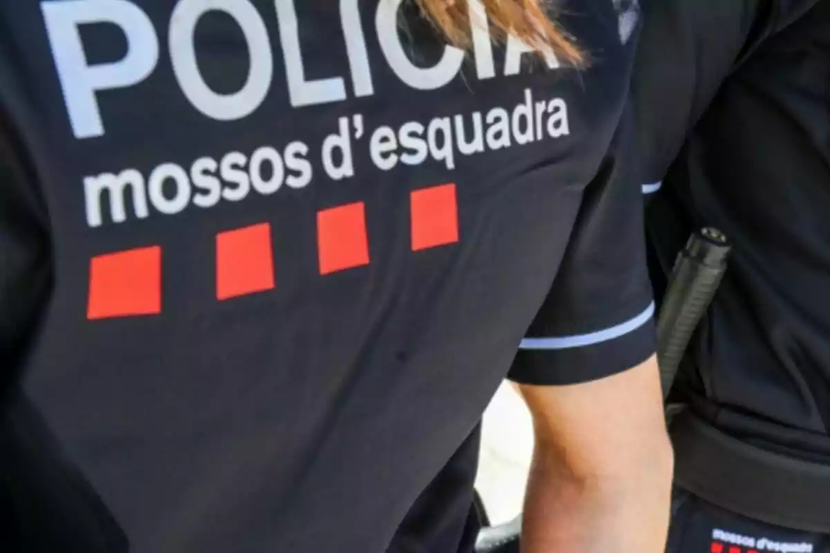 Uniforme d'un agent dels Mossos d'Esquadra amb la paraula "POLÍCIA" i quatre quadrats vermells.