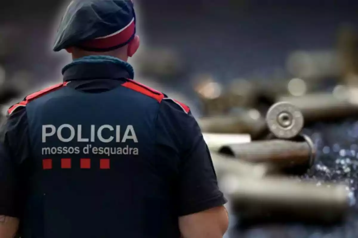 Un agente de los Mossos d'Esquadra de espaldas con un fondo de casquillos de bala desenfocado.