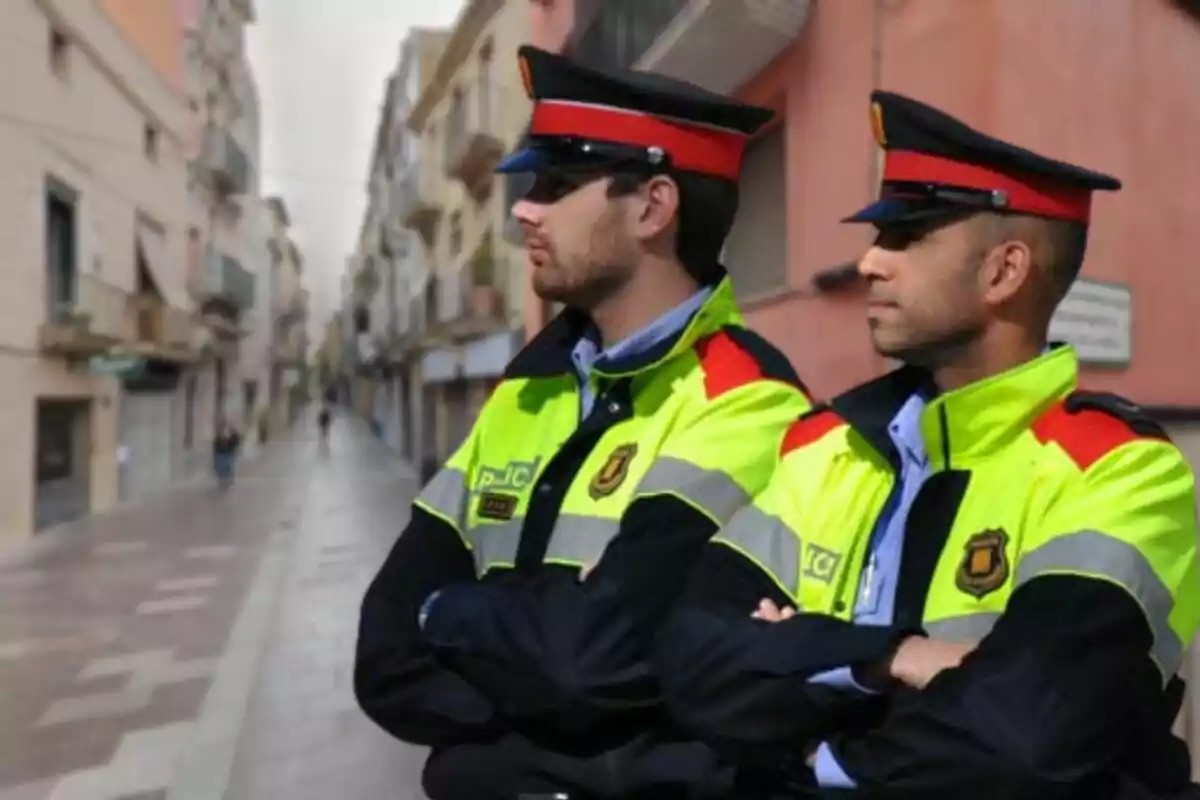 Dos policies amb uniformes d'alta visibilitat observen un carrer urbà.