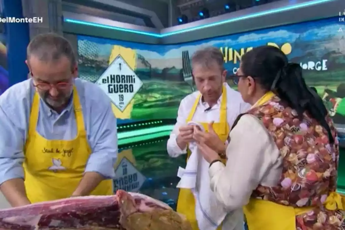 David de Jorge, María del Monte i Pablo Motos amb davantals grocs són a 'El Hormiguero', aparentment participant en una activitat culinària, mentre una gran peça de carn és sobre la taula davant d'ells. David de Jorge, María del Monte i Pablo Motos amb davantals grocs són a 'El Hormiguero', aparentment participant en una activitat culinària, mentre una gran peça de carn és sobre la taula davant d'ells.