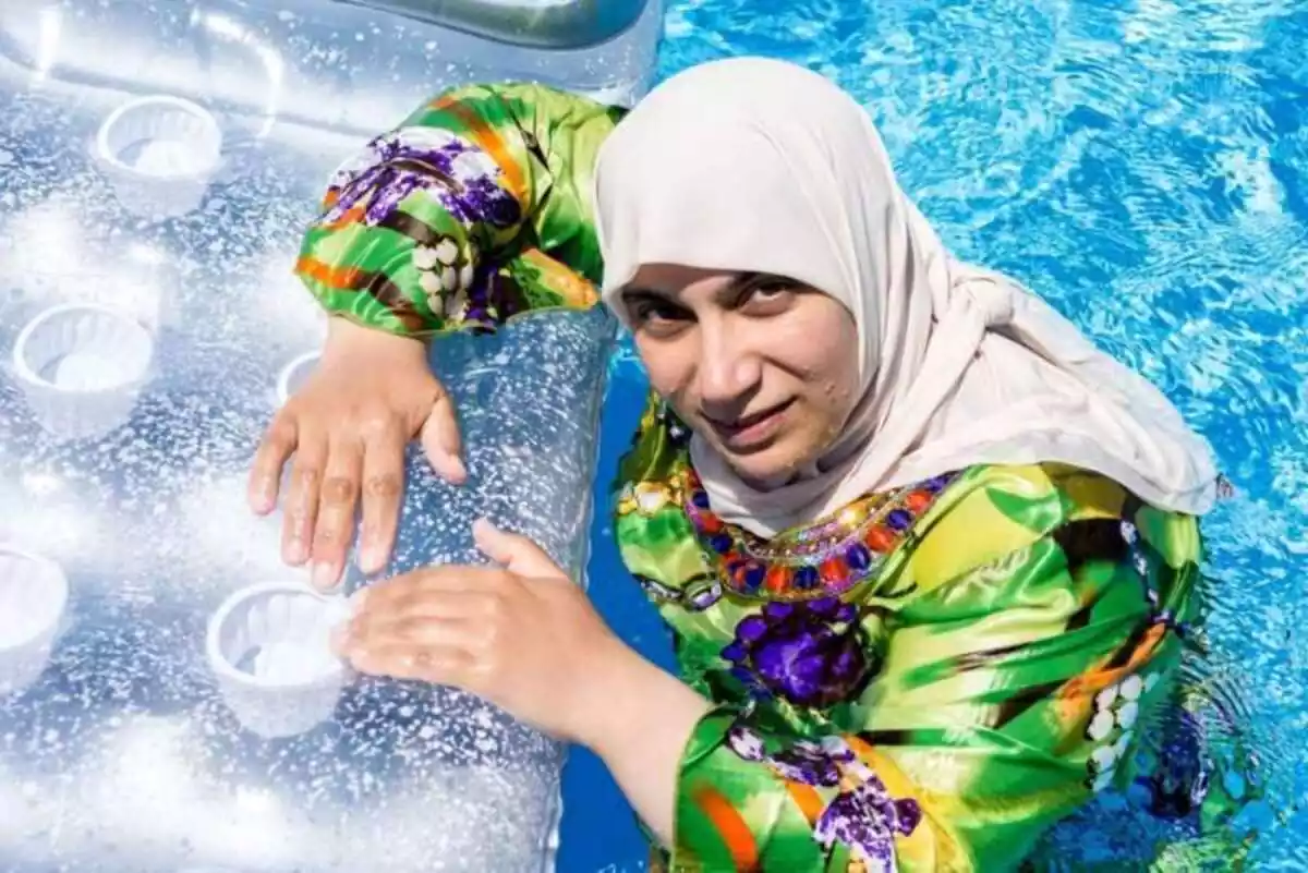 Imatge d'una dona amb burkini en una piscina subjectada a un matalàs inflable