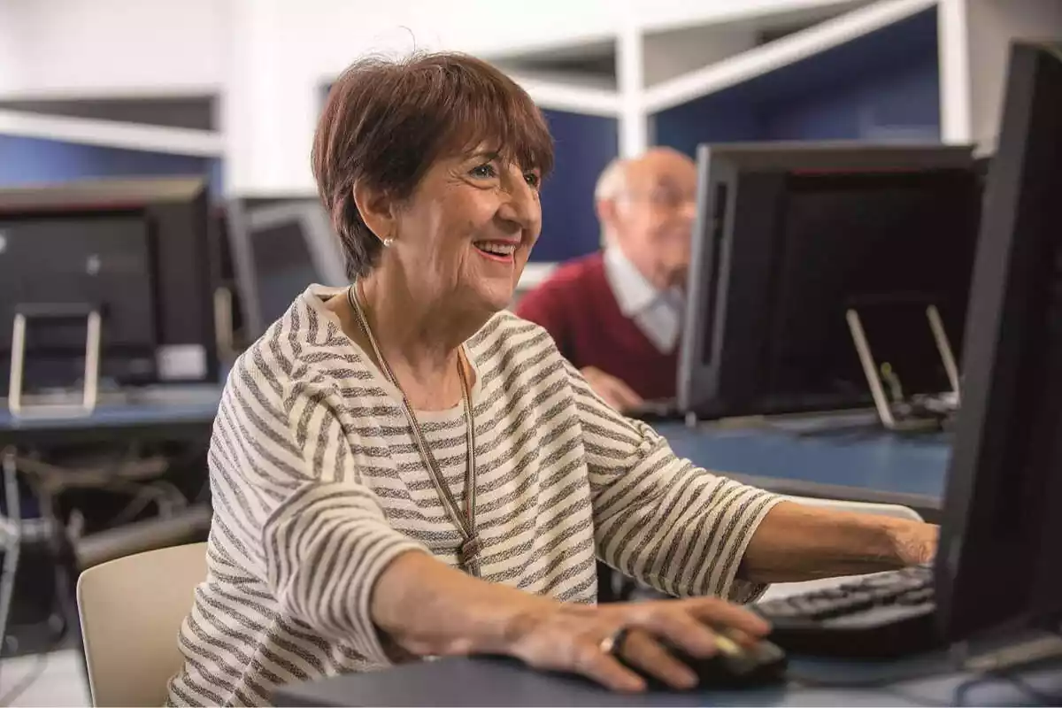 Dona major somrient i utilitzant un ordinador
