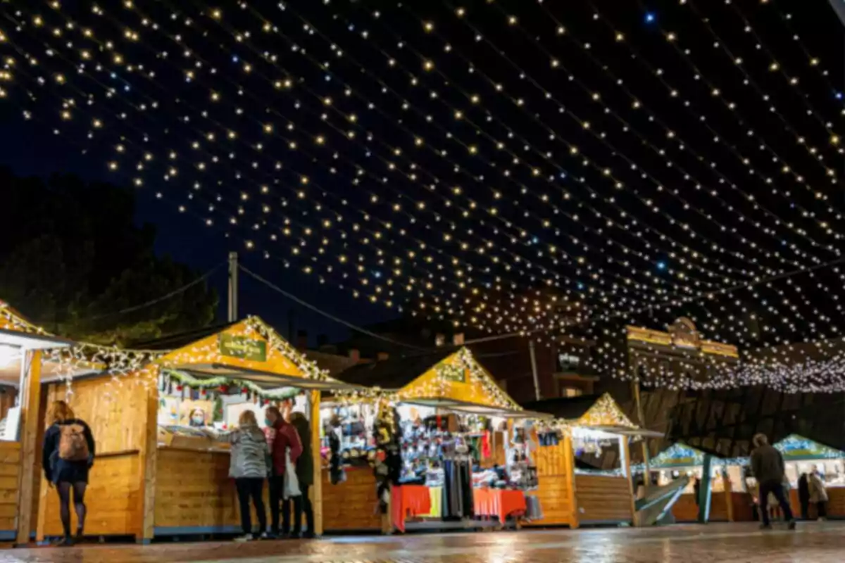 Mercat nadalenc a l'aire lliure amb llums brillants i parades de fusta il·luminades a la nit.